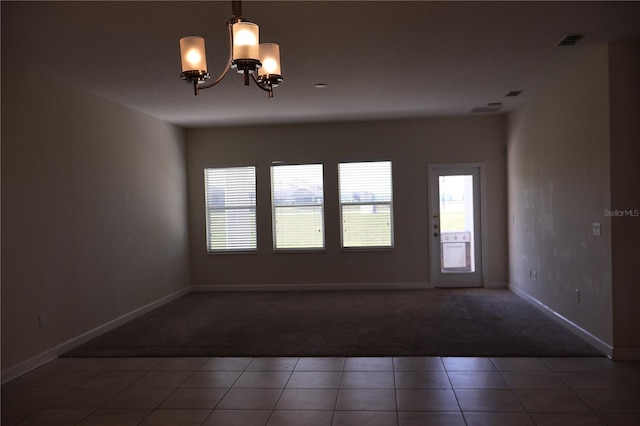 empty room featuring a chandelier and carpet floors