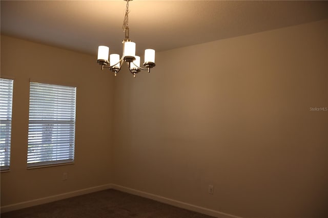 unfurnished room featuring a chandelier and dark colored carpet