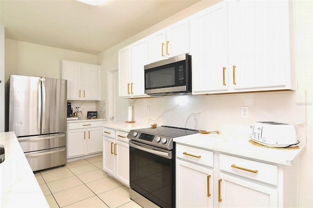 kitchen with white cabinets, light tile patterned floors, stainless steel appliances, and tasteful backsplash