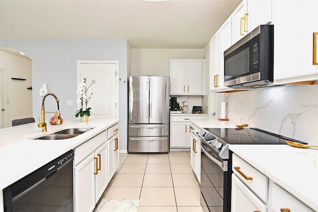 kitchen with backsplash, white cabinets, sink, light tile patterned floors, and appliances with stainless steel finishes