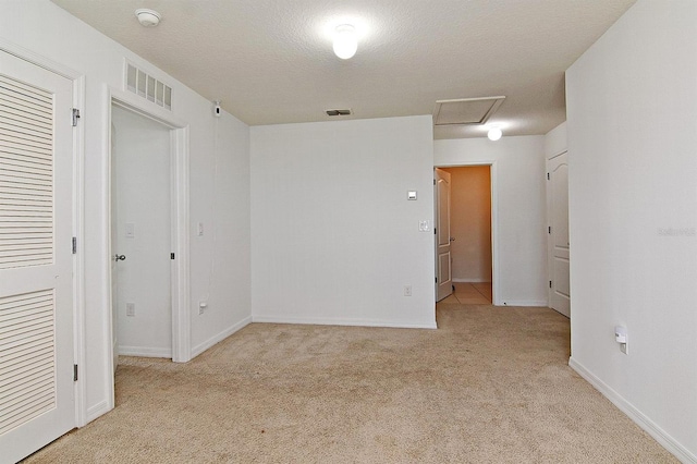 empty room featuring light colored carpet and a textured ceiling