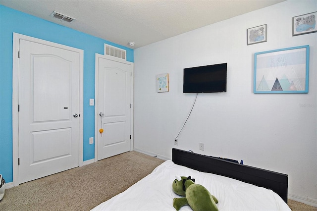 bedroom with a textured ceiling and light colored carpet