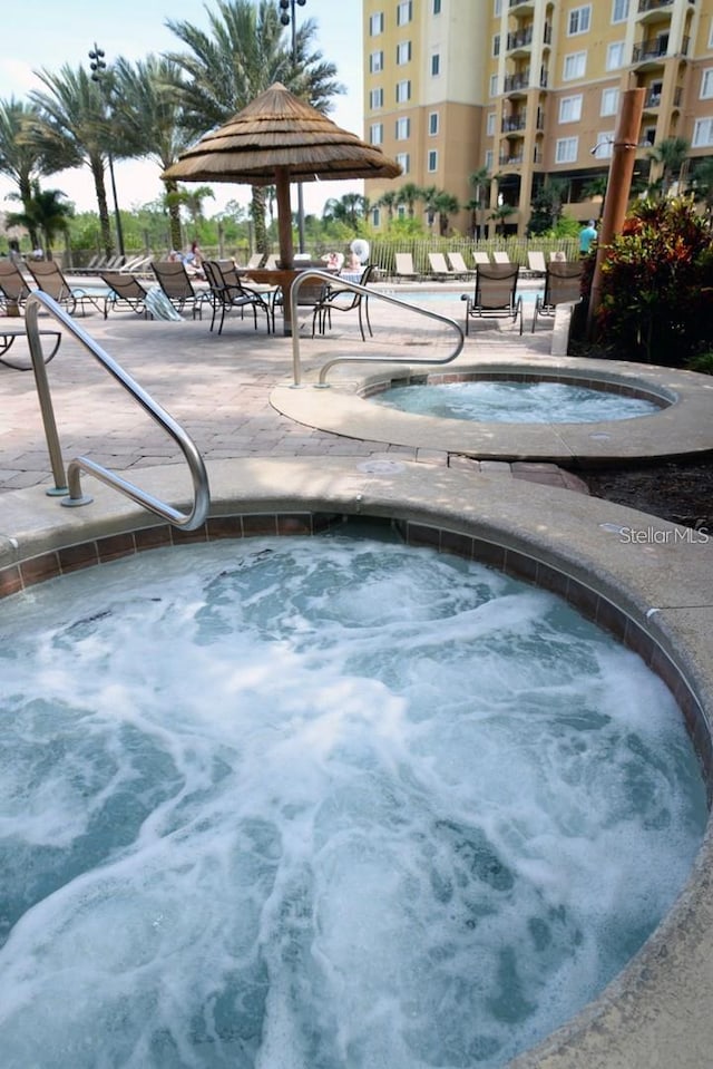 view of swimming pool featuring a community hot tub and a patio area