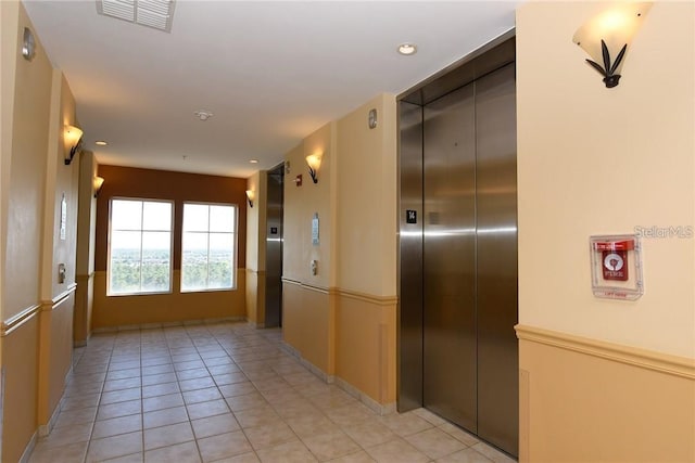 hallway with elevator and light tile patterned flooring