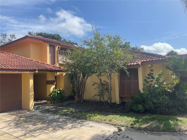 view of property exterior featuring a tile roof, an attached garage, and stucco siding