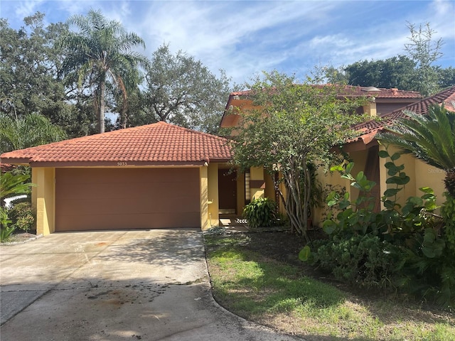 mediterranean / spanish house with stucco siding, a garage, concrete driveway, and a tiled roof