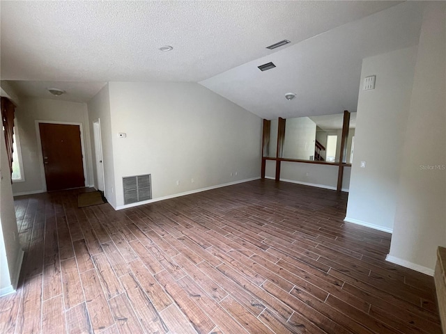 empty room with lofted ceiling, dark hardwood / wood-style floors, and a textured ceiling