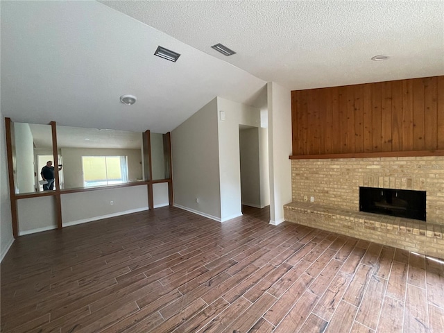 unfurnished living room with dark wood-type flooring, a textured ceiling, and a brick fireplace