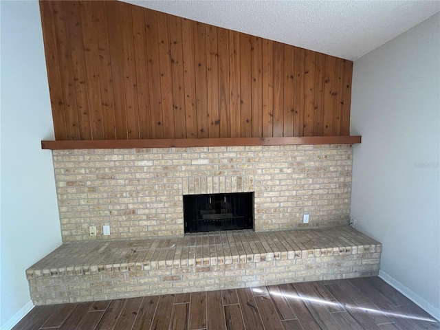 details featuring a textured ceiling, wooden walls, hardwood / wood-style flooring, and a fireplace