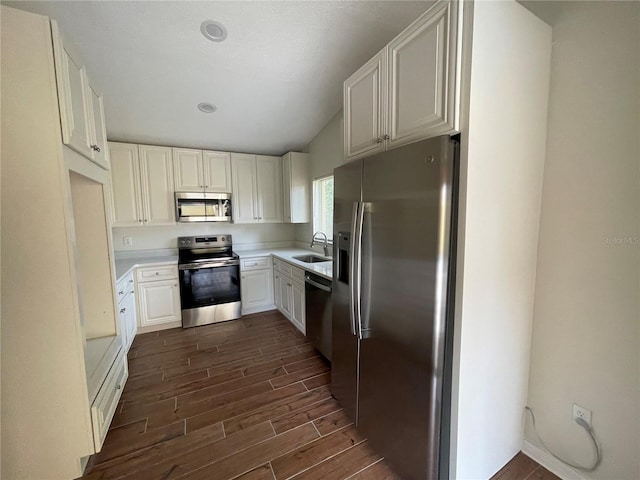 kitchen featuring white cabinetry, stainless steel appliances, dark hardwood / wood-style flooring, sink, and lofted ceiling