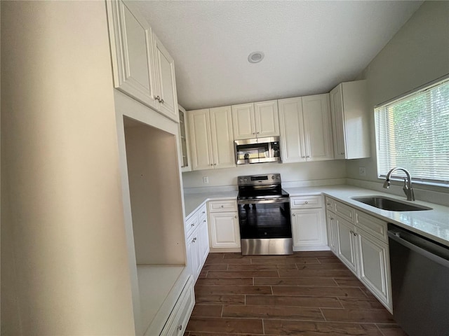 kitchen with white cabinets, appliances with stainless steel finishes, sink, dark hardwood / wood-style floors, and a textured ceiling