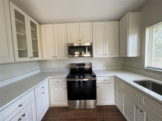 kitchen with dark wood-type flooring, white cabinetry, stainless steel appliances, and sink