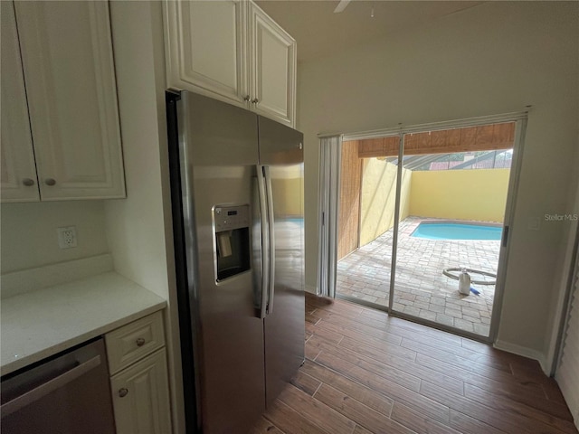 kitchen with appliances with stainless steel finishes, dark hardwood / wood-style flooring, and white cabinets