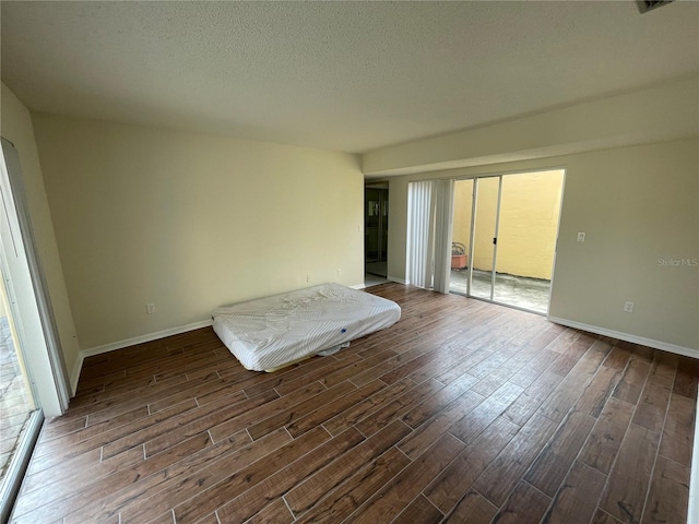 interior space featuring a textured ceiling, a wealth of natural light, and dark hardwood / wood-style floors