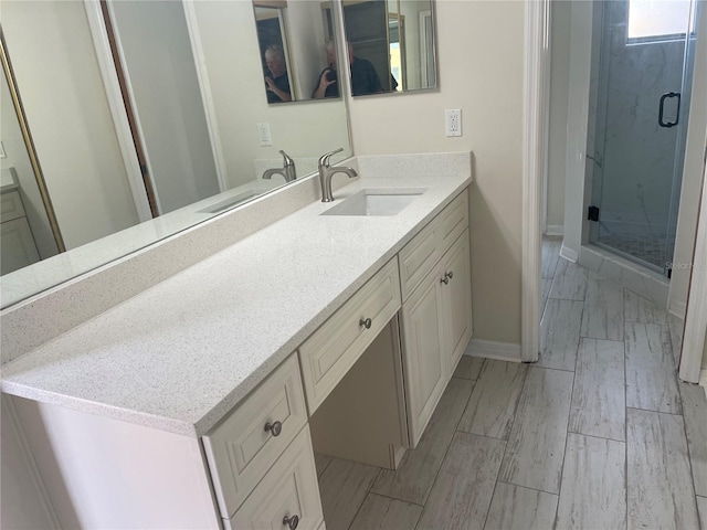 bathroom with a shower with shower door and vanity