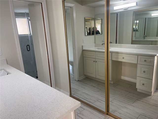 bathroom featuring vanity, toilet, and a shower with shower door