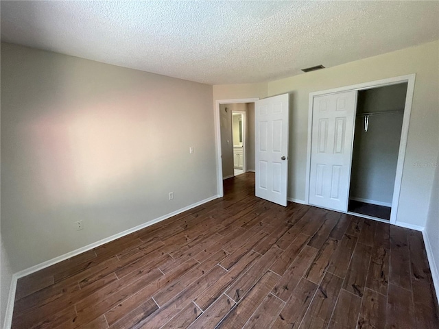 unfurnished bedroom with a closet, dark hardwood / wood-style flooring, and a textured ceiling