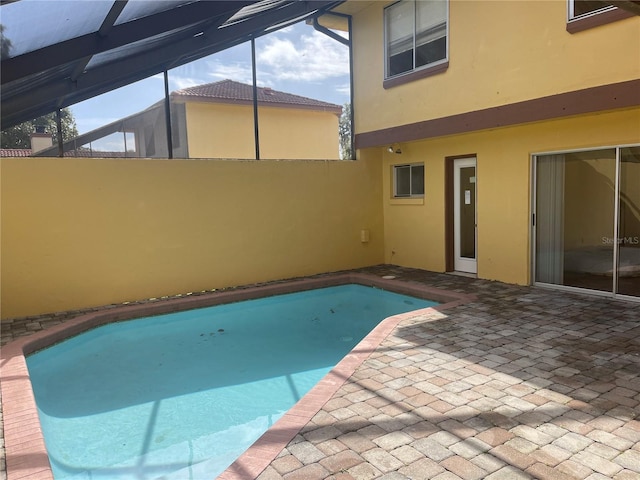 view of pool with glass enclosure and a patio