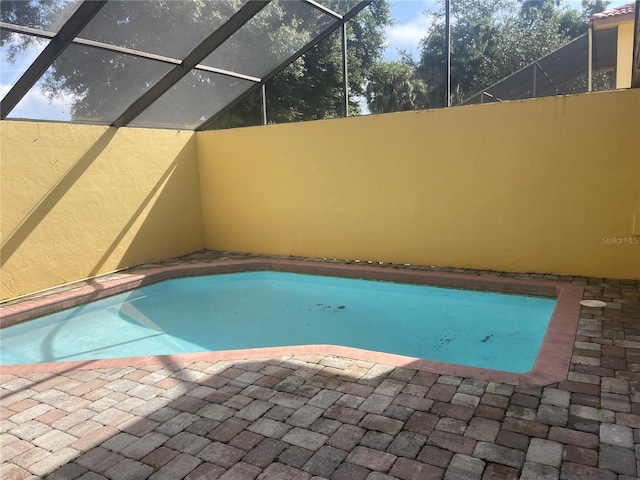 view of pool with glass enclosure and a patio area