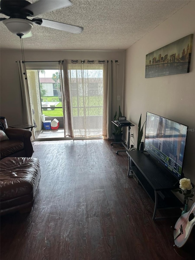 living room with dark wood-type flooring, ceiling fan, and a textured ceiling