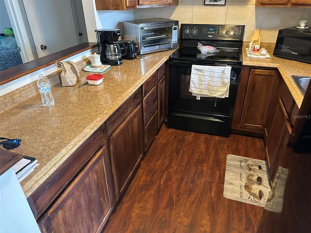 kitchen with black appliances, light stone counters, dark hardwood / wood-style floors, and tasteful backsplash