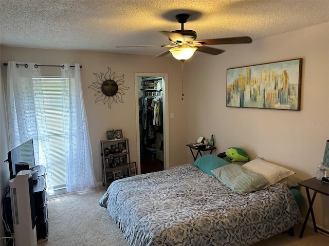 carpeted bedroom featuring a textured ceiling, ceiling fan, a walk in closet, and a closet