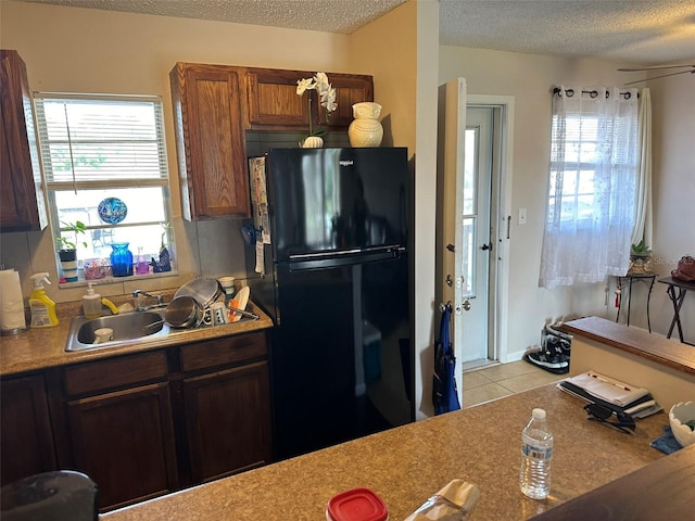 kitchen with a wealth of natural light, sink, black fridge, and a textured ceiling