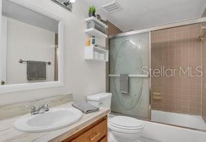 full bathroom with vanity, toilet, and combined bath / shower with glass door