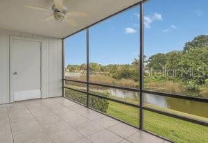 unfurnished sunroom featuring ceiling fan and a water view