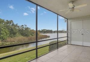 unfurnished sunroom featuring a water view and ceiling fan