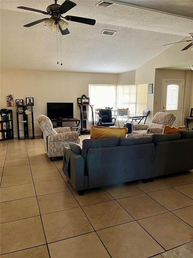 tiled living room featuring lofted ceiling, ceiling fan, and a textured ceiling