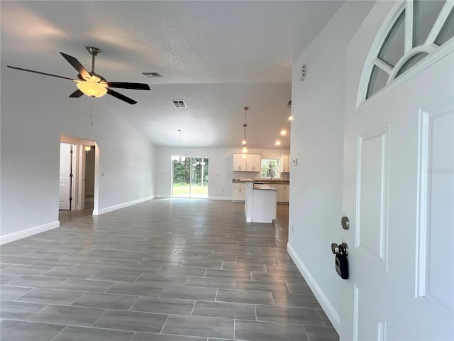 unfurnished living room with hardwood / wood-style flooring, a textured ceiling, sink, and ceiling fan with notable chandelier