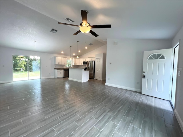 unfurnished living room featuring a textured ceiling, wood-type flooring, ceiling fan with notable chandelier, and vaulted ceiling