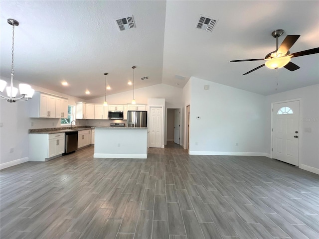 kitchen featuring appliances with stainless steel finishes, open floor plan, light wood-type flooring, and vaulted ceiling