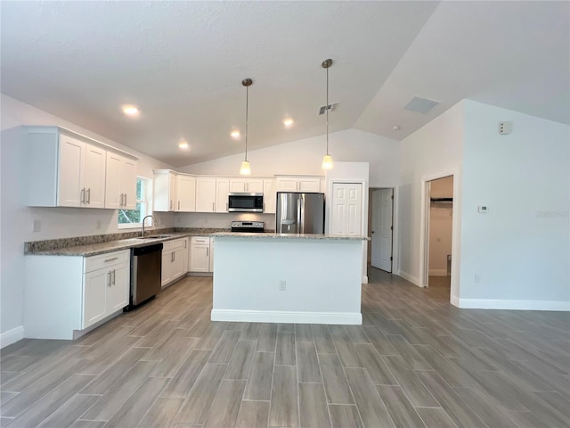 kitchen featuring appliances with stainless steel finishes, a center island, white cabinetry, lofted ceiling, and light hardwood / wood-style flooring