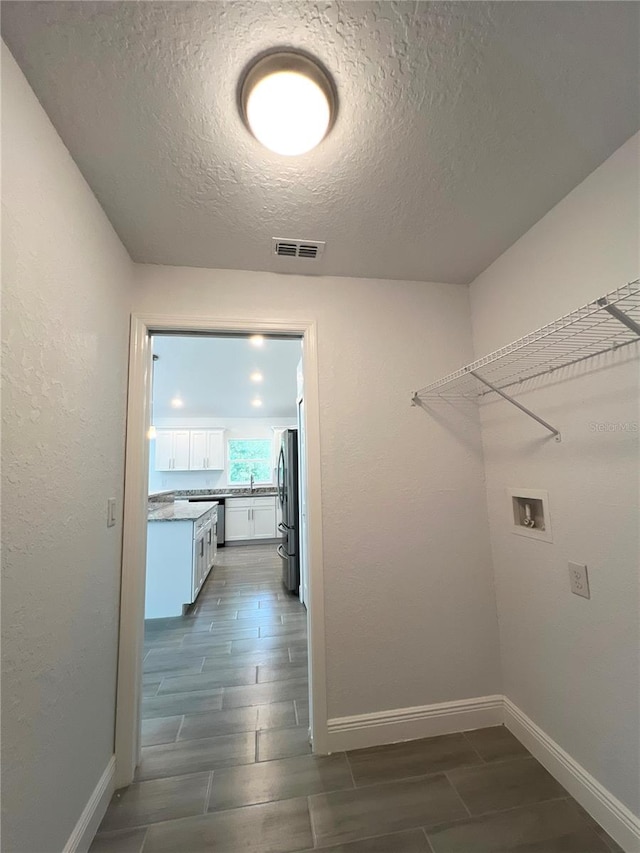 washroom with a textured ceiling, sink, and washer hookup