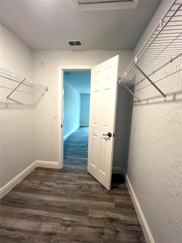 walk in closet with dark wood-style flooring