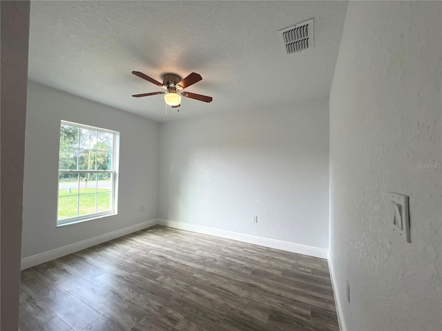 spare room featuring baseboards, a ceiling fan, wood finished floors, a textured ceiling, and a textured wall