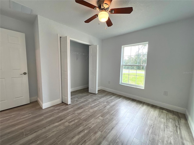 unfurnished bedroom with hardwood / wood-style flooring, a closet, and ceiling fan