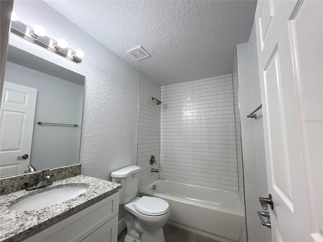 full bathroom with hardwood / wood-style flooring, toilet, tiled shower / bath combo, vanity, and a textured ceiling