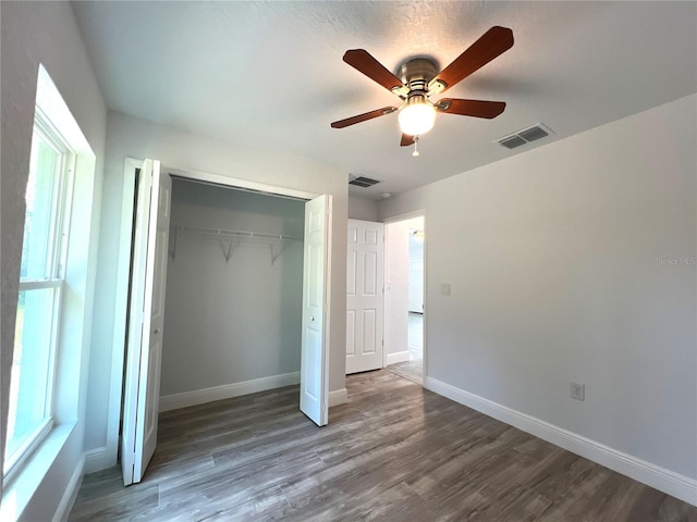unfurnished bedroom with wood finished floors, baseboards, a closet, and ceiling fan