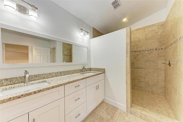 bathroom featuring vanity, vaulted ceiling, tile patterned floors, and tiled shower