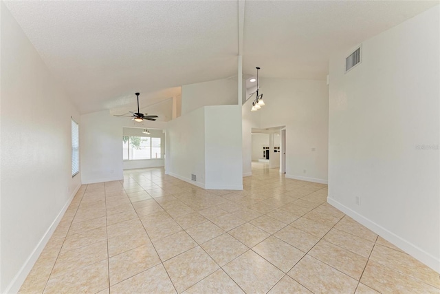 spare room featuring ceiling fan with notable chandelier, light tile patterned flooring, and vaulted ceiling