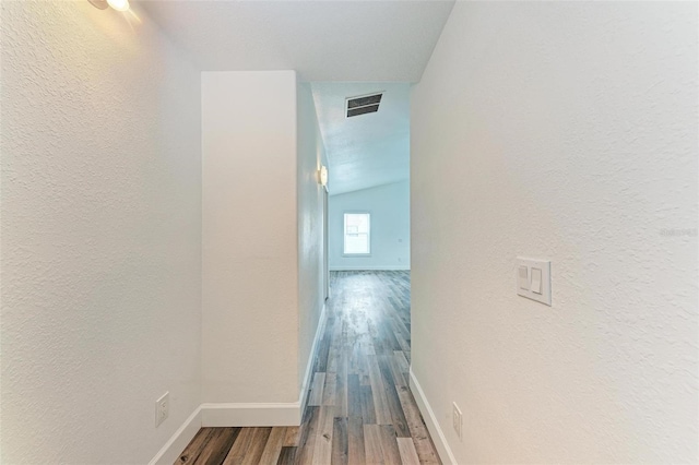 hallway featuring wood-type flooring and vaulted ceiling