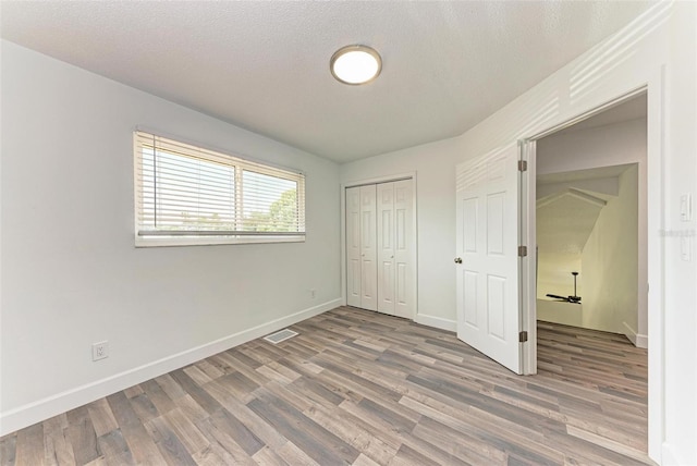 unfurnished bedroom featuring a closet, hardwood / wood-style floors, and a textured ceiling