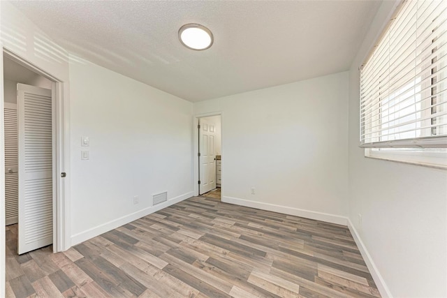 unfurnished bedroom with a closet, hardwood / wood-style floors, and a textured ceiling