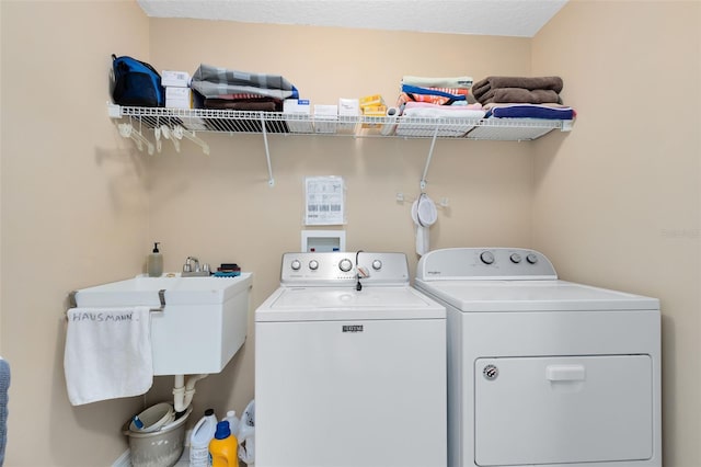 laundry room featuring sink, a textured ceiling, and washer and dryer