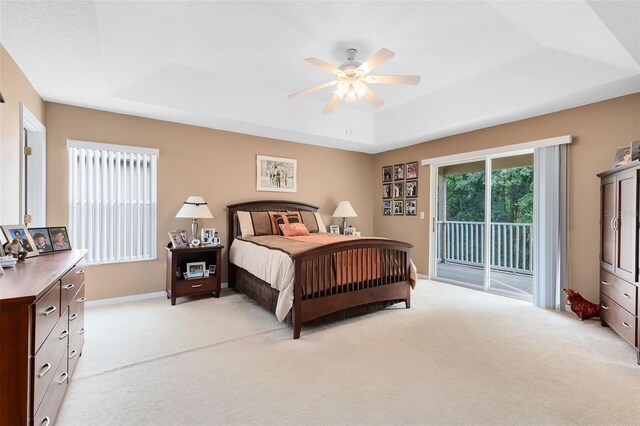 carpeted bedroom with ceiling fan, a tray ceiling, and access to outside