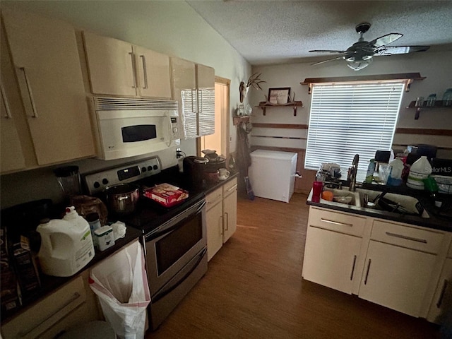 kitchen featuring a ceiling fan, a sink, stainless steel electric range oven, white microwave, and dark wood-style floors