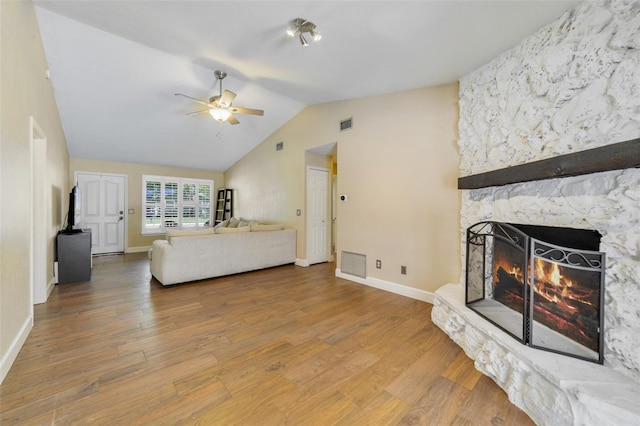 bedroom featuring lofted ceiling, ceiling fan, hardwood / wood-style floors, and a stone fireplace